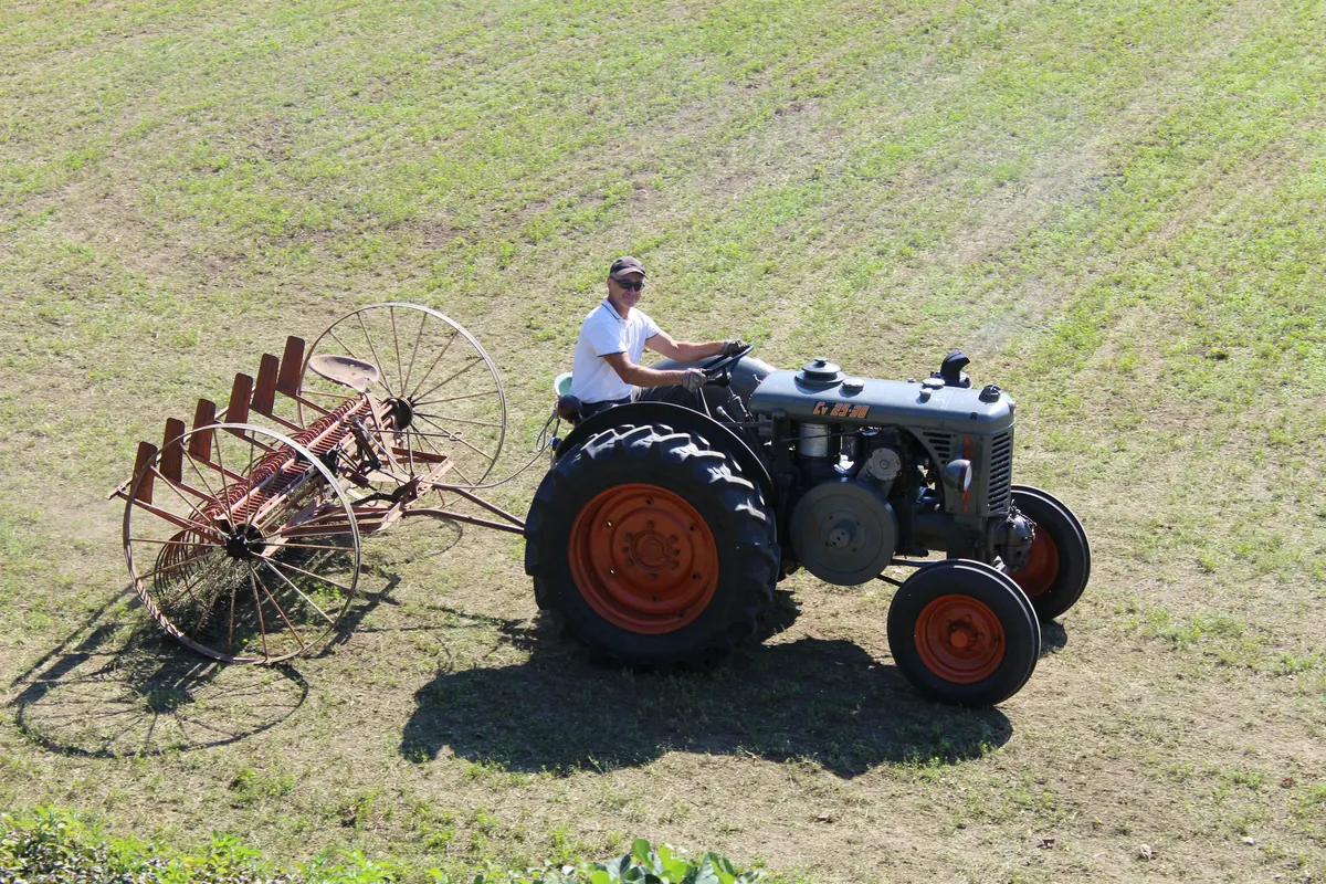 Il trattore e la rastrellona di profilo, visti dall’alto: le due grandi ruote di ferro e la fila di denti curvi